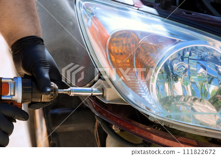 During car service while repairing car, repairman installs headlight During car service while repairing car, repairman installs headlight 111822672