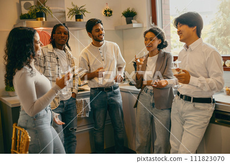 Group of smiling friends enjoying in conversation and drinking wine during Christmas party at home 111823070