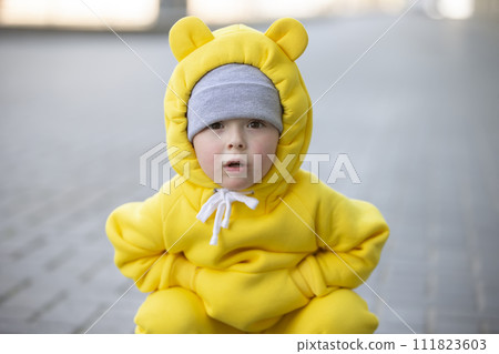 Funny little girl in a warm yellow suit with ears on a walk. Funny little girl in a warm yellow suit with ears on a walk. 111823603