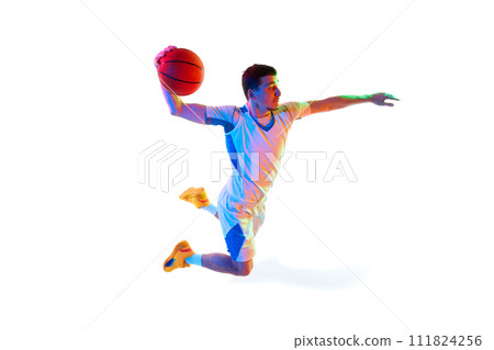 Focused basketball player in game progress doing powerful dunk in motion against white studio background in neon light. 111824256