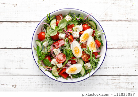 Egg and arugula fresh vegetable salad with feta cheese, top view 111825087