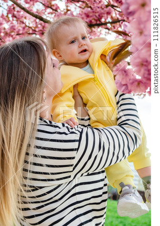 Mom and baby enjoying beautiful sakura tree in spring. Mom and baby enjoying beautiful sakura tree in spring. 111826515