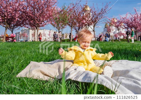 Little boy taking in the fresh air and sunshine on a soft green blanket. 111826525