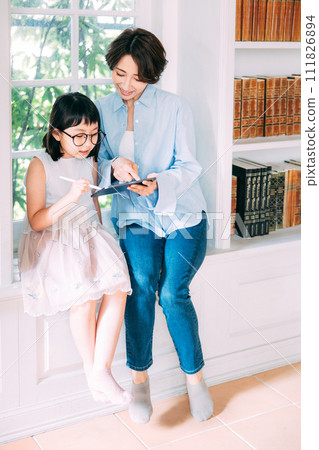 A girl looking at a tablet with her mother A girl looking at a tablet with her mother 111826894