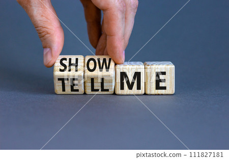 Tell or show me symbol. Businessman turns beautiful wooden cubes and changes words Tell me to Show me. Beautiful grey table grey background. Business tell or show me concept. Copy space. 111827181