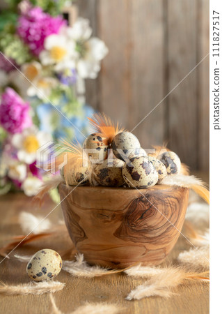 Easter composition with quail eggs, feathers, and spring flowers on a old wooden table. 111827517