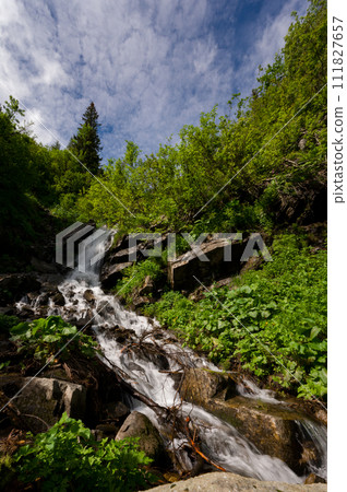 Mountain waterfall on the background of the sky with a summer sunny day. 111827657