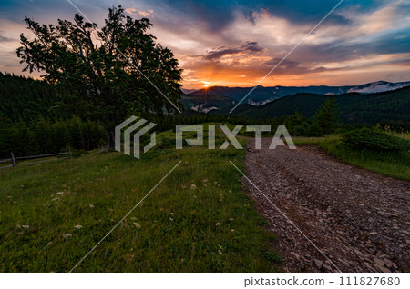 Magical dawn in the Carpathians, a road for tourists in the foreground. Magical dawn in the Carpathians, a road for tourists in the foreground. 111827680