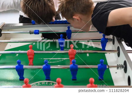 Active recreation in the game room, children play table football. 111828204