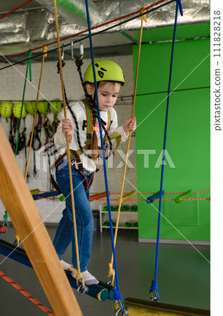 A little girl walks on a cableway, a playroom with a cable car. A little girl walks on a cableway, a playroom with a cable car. 111828218