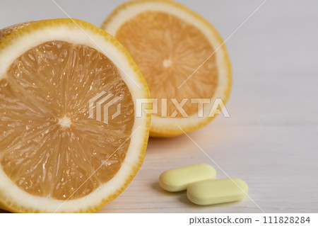 The concept of vitamin C in a minimalist style. Natural vitamin C in lemon versus synthetic vitamin C in tablets. Alternative medicine. A food additive. The concept of vitamin C in a minimalist style. Natural vitamin C in lemon versus synthetic vitamin C in tablets. Alternative medicine. A food additive. 111828284