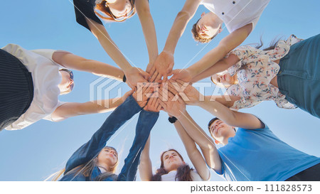 Friends putting their hands together in a sign of unity and teamwork. Just the hands. Friends putting their hands together in a sign of unity and teamwork. Just the hands. 111828573