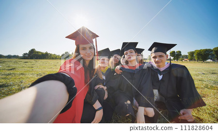 College alumni take selfies in the meadow. 111828604