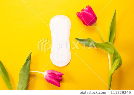 Feminine hygiene pad and tulip on yellow background. First menstrual period concept Feminine hygiene pad and tulip on yellow background. First menstrual period concept 111829249