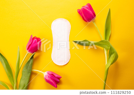 Feminine hygiene pad and tulip on yellow background. First menstrual period concept Feminine hygiene pad and tulip on yellow background. First menstrual period concept 111829250