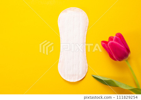 Feminine hygiene pad and tulip on yellow background. First menstrual period concept 111829254