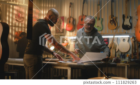 Two carpenters discuss process of making wooden guitar Two carpenters discuss process of making wooden guitar 111829263