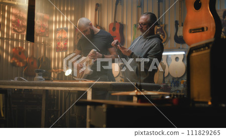 Two carpenters make wooden guitar and take measurements 111829265