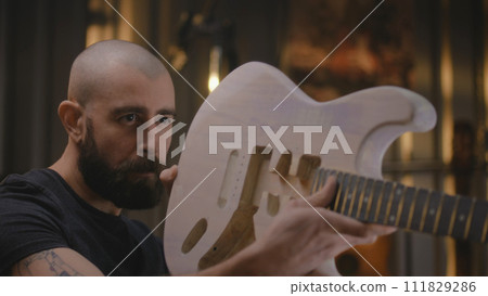Close up shot of male craftsman attaching guitar neck to the guitar body 111829286