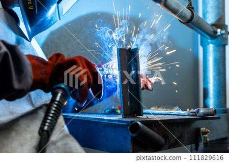 Welder worker welding a pieces of metal in the industrial factory, heavy weld industry concept 111829616