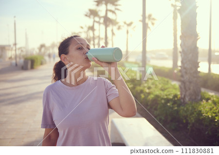 Wellness and health. Young female athlete, sportswoman with bottle of fresh clear water after sports workout outdoors Wellness and health. Young female athlete, sportswoman with bottle of fresh clear water after sports workout outdoors 111830881