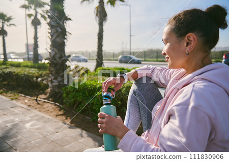 Authentic portrait of a relaxed young woman with a bottle of water, 111830906