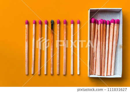 Success, defeat, achievement. The concept of happiness. Matches on a yellow background. Burnt dark match among normal matches. Burning match fire to its neighbors, a metaphor for ideas and inspiration 111831627