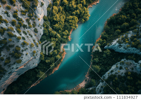 An aerial view of a serene turquoise river winding through a lush gorge with dense greenery and rocky cliffs, encapsulating the tranquil beauty and untouched wilderness. 111834927