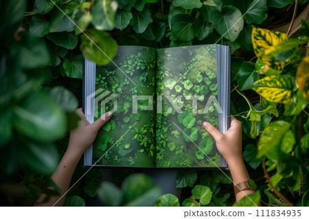Hands hold open a book with vibrant green foliage imagery, blending seamlessly into the surrounding lush environment, illustrating the story of nature's beauty. 111834935