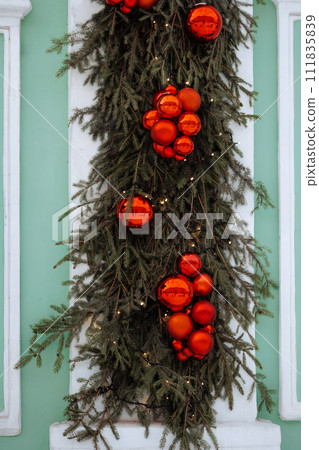 Christmas garland with red ornaments on door. 111835839
