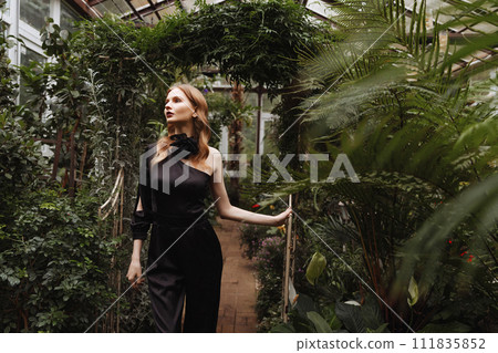 A woman walking through a greenhouse. 111835852