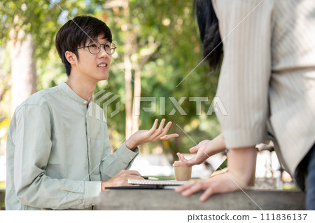 A smart Asian male student is sharing his ideas with his friend while collaborating on work together A smart Asian male student is sharing his ideas with his friend while collaborating on work together 111836137