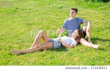 Happy romantic couple sitting on grass in day Happy romantic couple sitting on grass in day 111836611