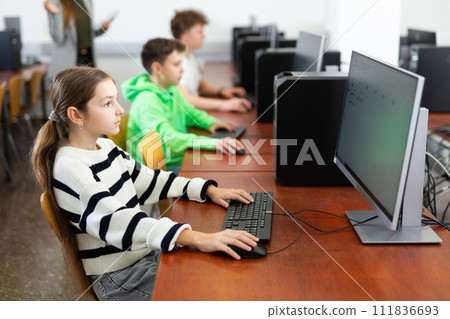 Portrait of schoolgirl at computers in university computer class Portrait of schoolgirl at computers in university computer class 111836693