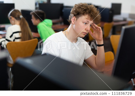 Thoughtful teenager boy using PC during computer science lesson 111836729