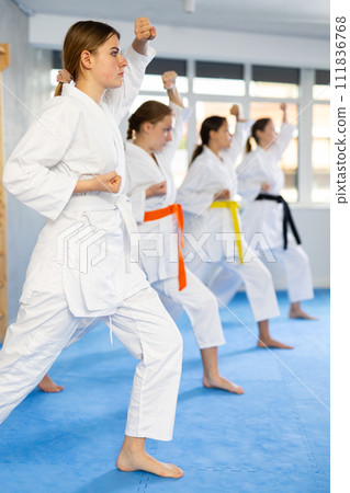 Teenage girl with group in kimonos performing kata to hone martial arts skills 111836768
