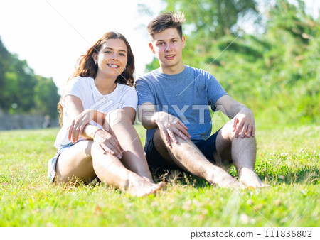 Happy romantic couple sitting on grass in day 111836802