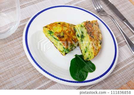 Few small pieces of fluffy egg and spinach omelet are on plate decorated with edible green Few small pieces of fluffy egg and spinach omelet are on plate decorated with edible green 111836858
