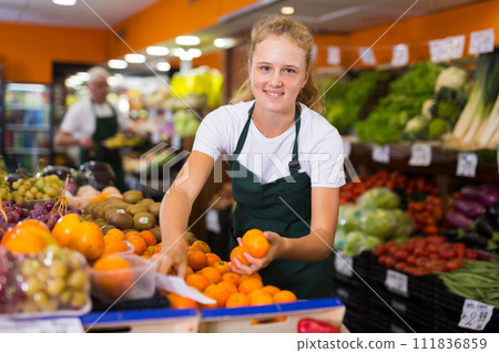 Fifteen-year-old girl who works part-time as a trainee saleswoman puts tangerines 111836859