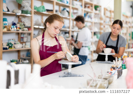 Teenage girl painting ceramic cup in ceramic workshop 111837227