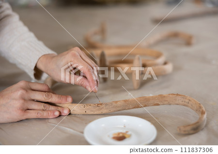 close-up of hands of cabinetmaker restoring wooden decor element of antique furniture close-up of hands of cabinetmaker restoring wooden decor element of antique furniture 111837306