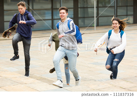 Group of cheerful students running along city street Group of cheerful students running along city street 111837316