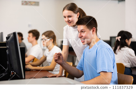 Smiling teenagers using computer during computer science lesson Smiling teenagers using computer during computer science lesson 111837329