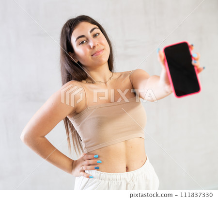 Young smiling woman posing with phone in studio Young smiling woman posing with phone in studio 111837330