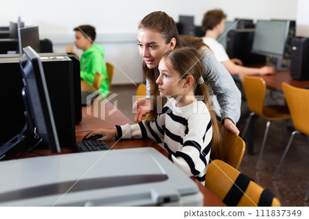 Teacher helping girl to solve computer problem 111837349