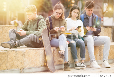 Teenagers are playing on smartphone on street Teenagers are playing on smartphone on street 111837403