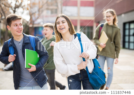 Two positive teens walk along street 111837446