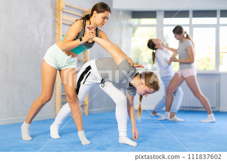 Two teenage girls training in group self defense classes 111837602