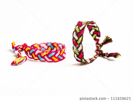 Multicolored woven DIY friendship bracelets handmade of embroidery bright thread with knots isolated on white background Multicolored woven DIY friendship bracelets handmade of embroidery bright thread with knots isolated on white background 111838625