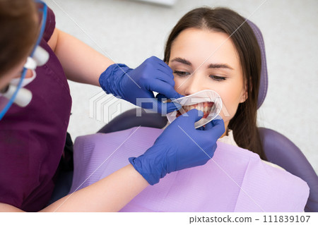Orthodontist inserts an elastic ring into the mouth of the patient Orthodontist inserts an elastic ring into the mouth of the patient 111839107
